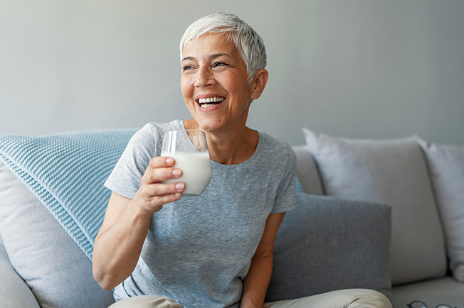 Older lady holding a glass of milk looking happy