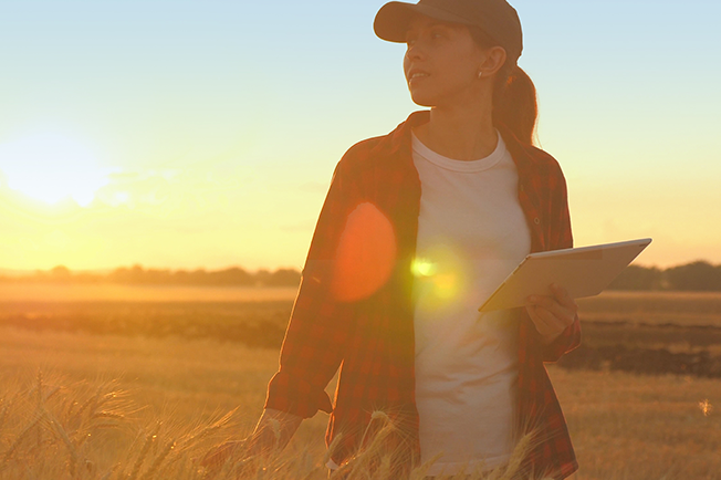 Women walking through a field with the sun behind her